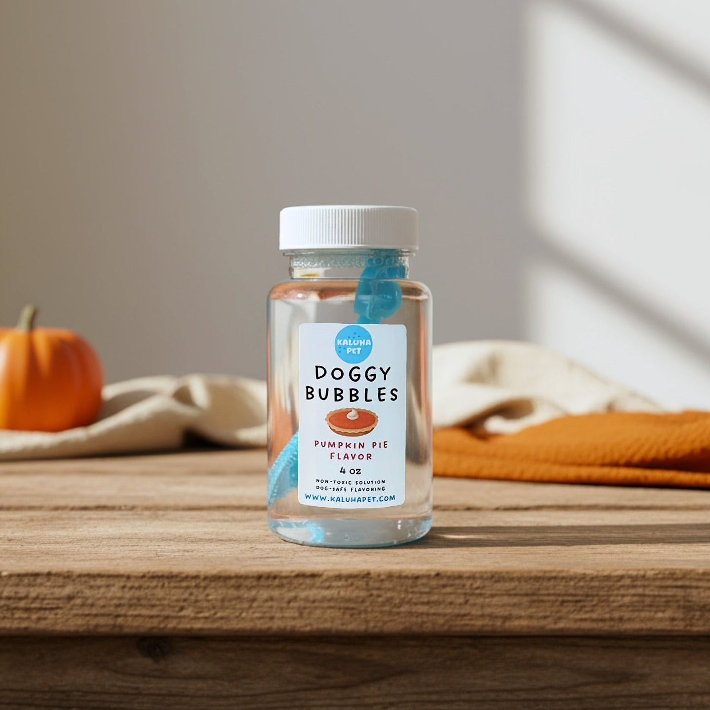 Bottle of pumpkin pie flavored 'Doggy Bubbles' on a wooden table with a pumpkin in the background